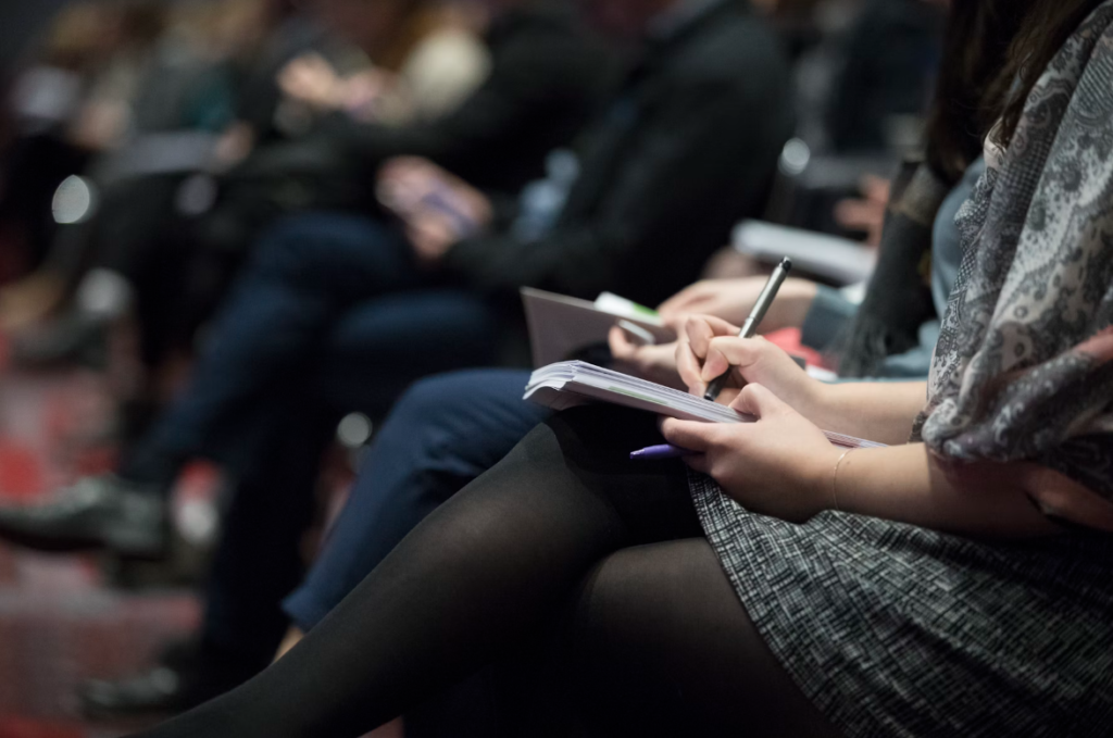 A close up image of a woman taking notes at a business meeting.
