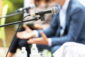 Microphone in focus against blurred people at round table event or business conference.