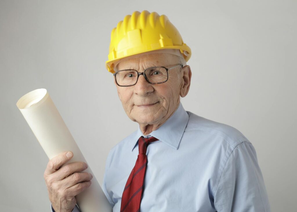 Senior engineer in safety gear holding blueprints, symbolizing experience and dedication in civil engineering.