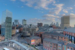 Cityscape shows several buildings under a cloudy sky.